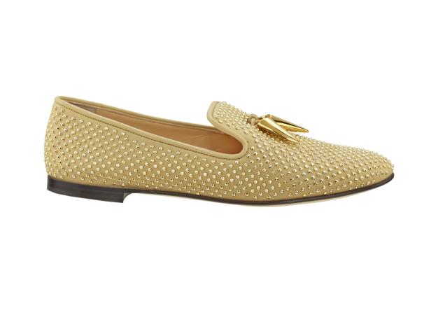 Ein beiger Slipper ist mit goldenen Nieten und goldenen Zierelementen verziert.