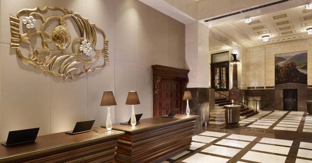 Die Rezeption eines Hotels mit dekorativer Wandkunst und Laptop-Arbeitsplätzen.