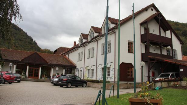 Ein großes, weißes Gebäude mit einem Parkplatz und mehreren Autos davor.