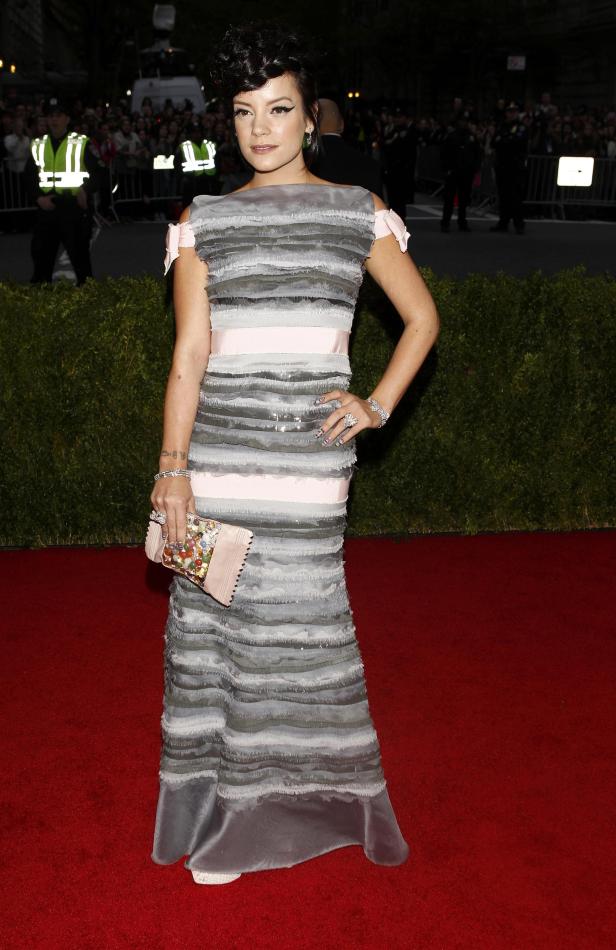 Lily Allen in einem gestreiften, bodenlangen Kleid auf einem roten Teppich.