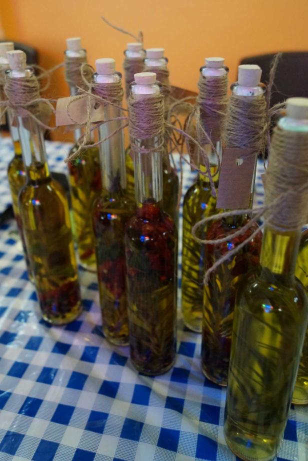 Mehrere Flaschen mit aromatisiertem Öl stehen auf einem blau-weiß karierten Tuch.