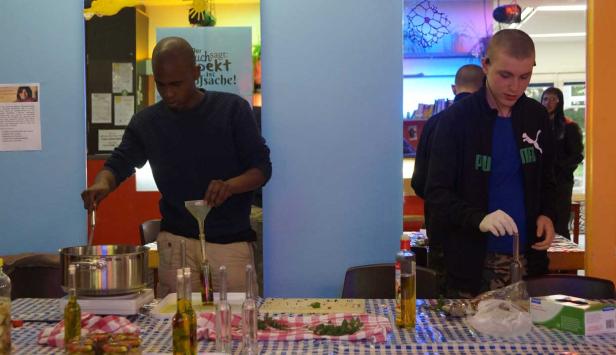 Zwei Personen füllen Kräuteröl in Flaschen ab.