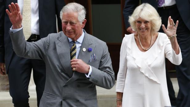 König Charles III. und Königin Camilla winken lächelnd in die Menge.