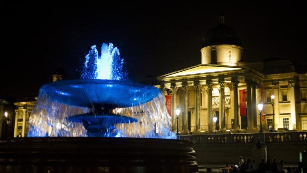 Der Trafalgar Square in London mit dem beleuchteten Brunnen und der National Gallery bei Nacht.