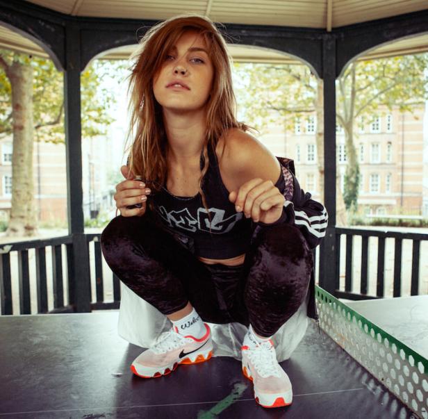 Eine junge Frau hockt auf einem Tischtennistisch in einem Pavillon.