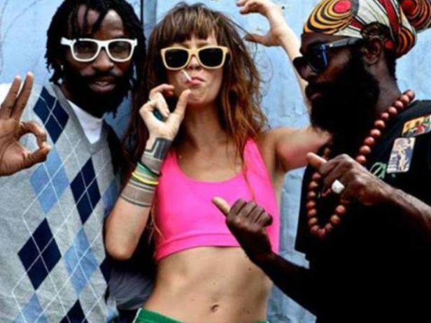 Drei Personen posieren mit Sonnenbrillen und lässiger Kleidung vor einer Wand.