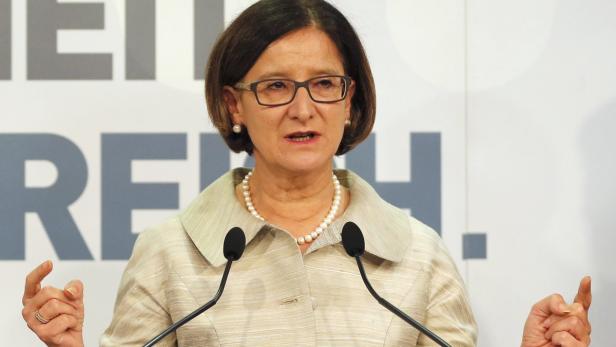 Eine Frau mit Brille und Perlenkette spricht an einem Rednerpult.