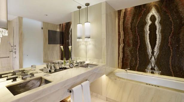 Ein luxuriöses Badezimmer mit Marmorwaschtisch, Badewanne und dekorativer Wand.