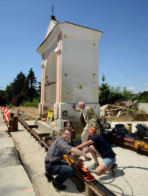 Eine himmlische Reise Drei Männer arbeiten an einer Kapelle, die auf Schienen steht.