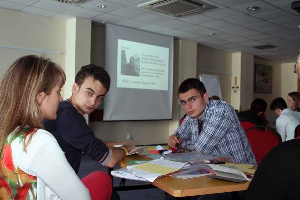 Mehrere Personen sitzen in einem Raum und arbeiten an einem Tisch.