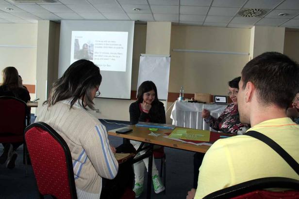 Eine Gruppe von Personen sitzt an einem Tisch während einer Präsentation.