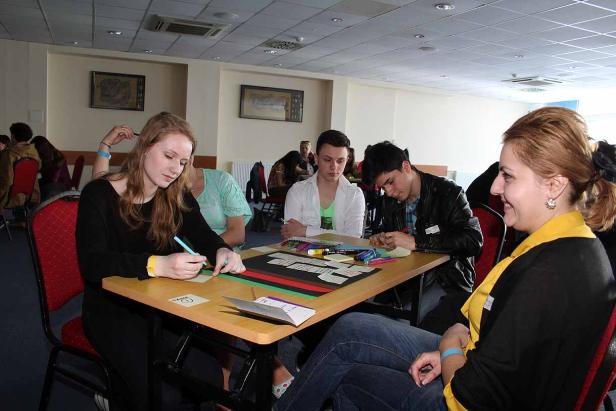 Eine Gruppe junger Leute sitzt an einem Tisch und arbeitet an einem Projekt.