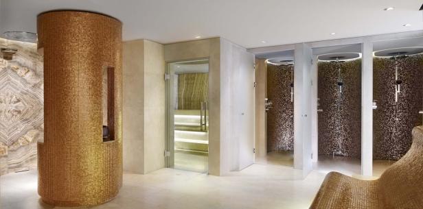 Ein luxuriöser Spa-Bereich mit goldenen Mosaikdetails und mehreren Duschen.