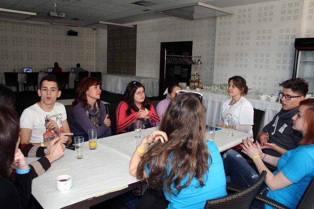 Eine Gruppe junger Leute sitzt an einem Tisch und unterhält sich.