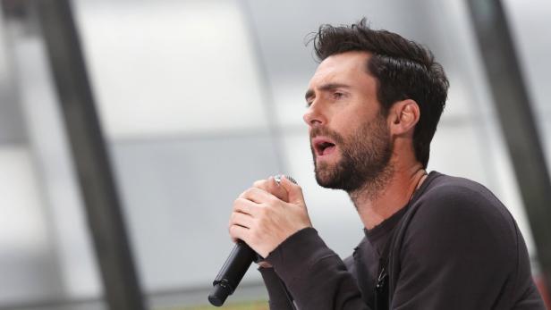 Adam Levine singt in ein Mikrofon.