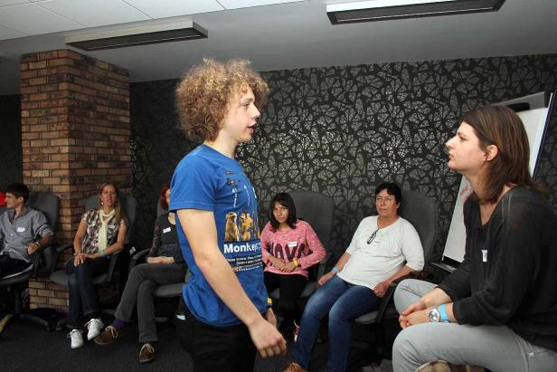 Ein junger Mann spricht vor einer Gruppe von Zuhörern in einem Raum.