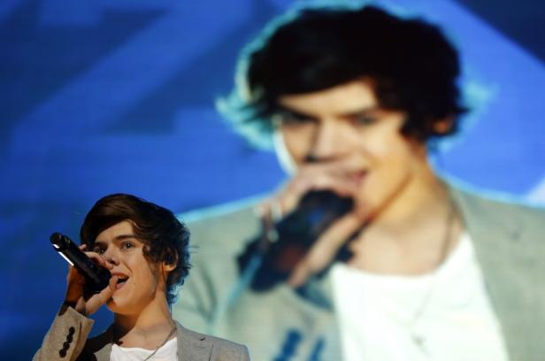 Harry Styles singt vor einem großen Bildschirm.