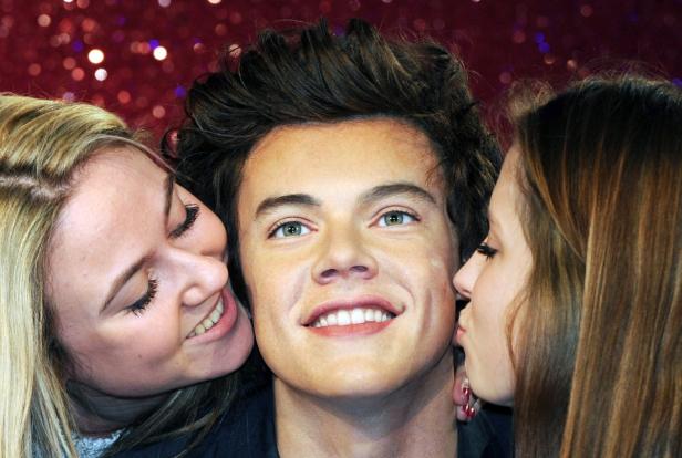 Zwei Frauen küssen die Wachsfigur von Harry Styles.