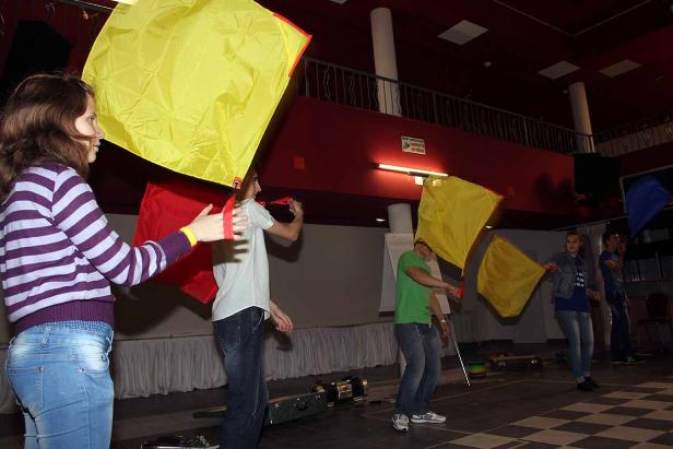 Eine Gruppe von Menschen schwingt farbige Flaggen in einem Raum.