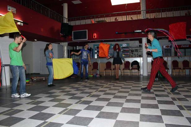 Eine Gruppe von Personen jongliert mit Tüchern und Bällen in einem Raum.