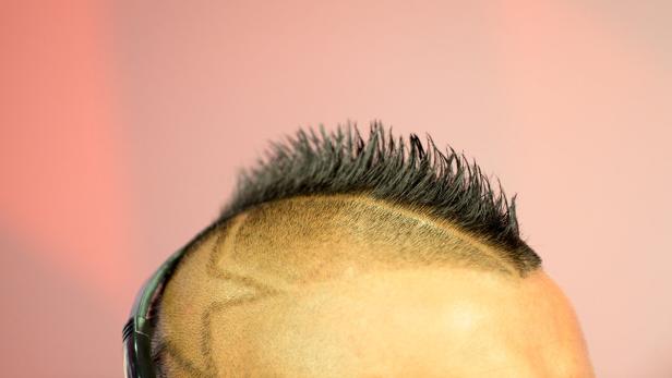 Nahaufnahme des Kopfes einer Person mit einem Irokesenschnitt und Kopfhörern.