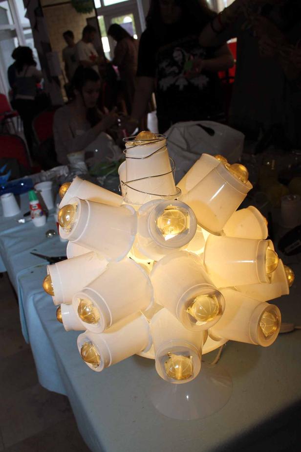 Eine Lampe, die aus vielen aneinandergeklebten Plastikbechern besteht.
