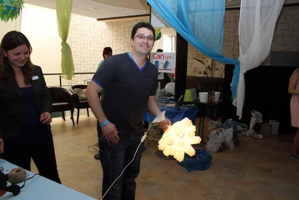 Ein Mann präsentiert eine selbstgebaute Lampe aus Plastikbehältern.