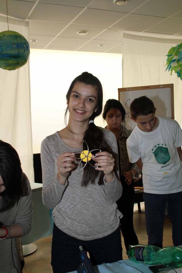 Ein junges Mädchen hält eine selbstgebastelte Blume aus Papier in den Händen.