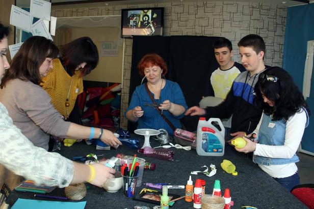 Eine Gruppe von Leuten bastelt an einem Tisch mit verschiedenen Materialien.