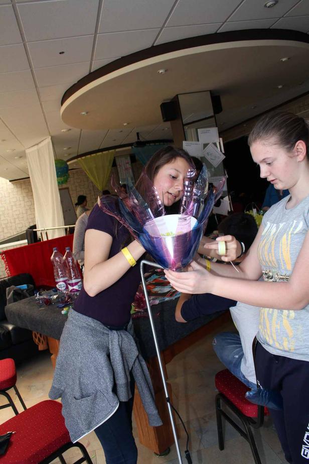 Zwei junge Frauen basteln gemeinsam an einer blauen Dekoration aus Plastikflaschen.