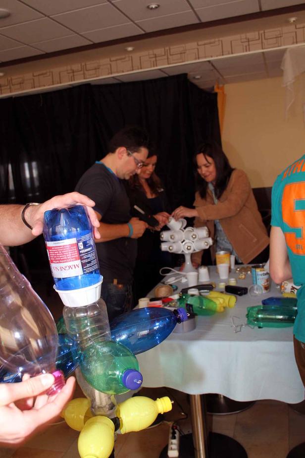 Menschen basteln mit Plastikflaschen und anderen Materialien an einem Tisch.