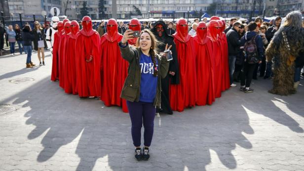 Eine Frau macht ein Selfie mit als „Star Wars“-Charaktere verkleideten Personen.