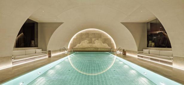 Ein Innenpool mit hellblauem Wasser und einer Skulptur an der Wand.