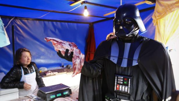 Darth Vader im Kostüm verkauft Fleisch an einem Marktstand.