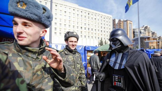 Zwei Soldaten stehen neben einer als Darth Vader verkleideten Person.