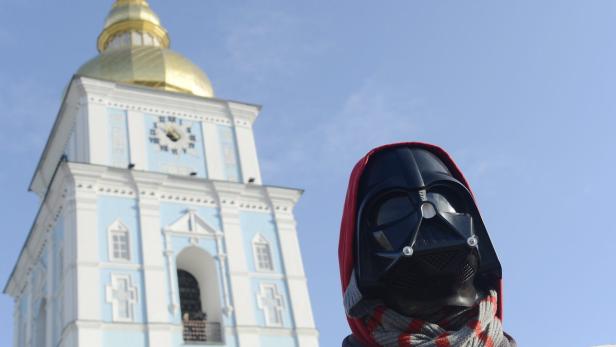 Eine Person in Darth Vader-Maske vor dem Hintergrund einer Kirche mit goldenem Turm.