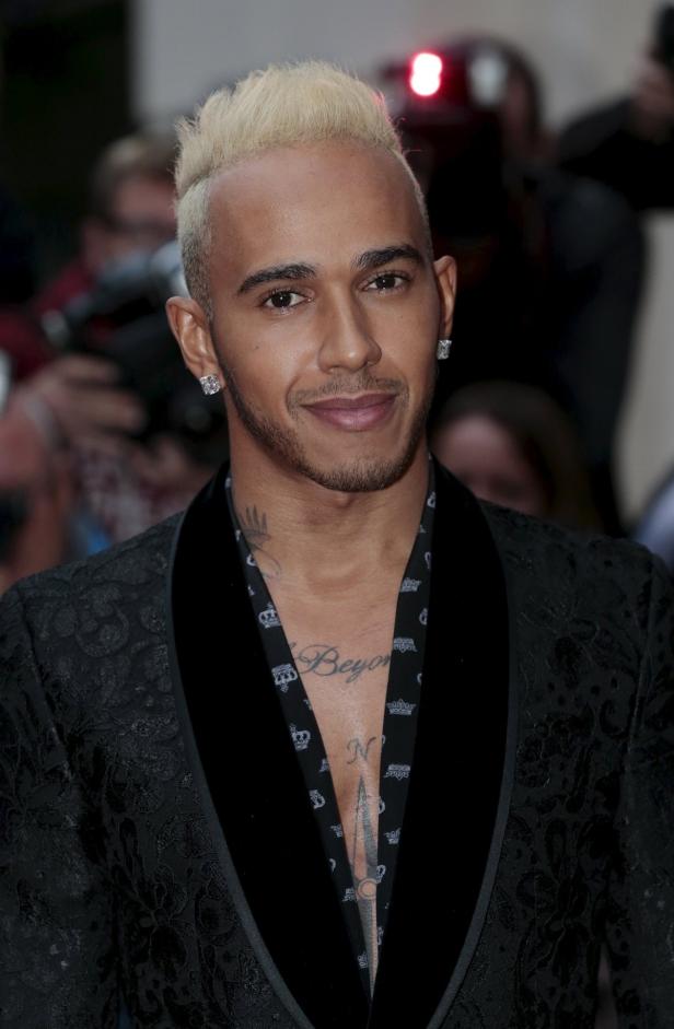 Lewis Hamilton mit blond gefärbten Haaren und Tätowierungen auf Brust und Hals.