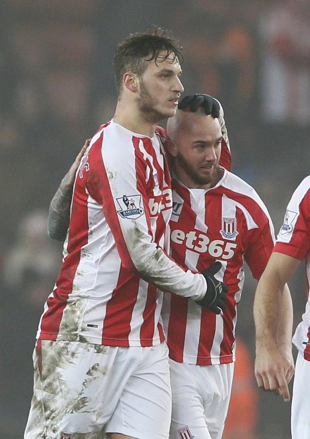 Zwei Fußballspieler in rot-weiß gestreiften Trikots umarmen sich.