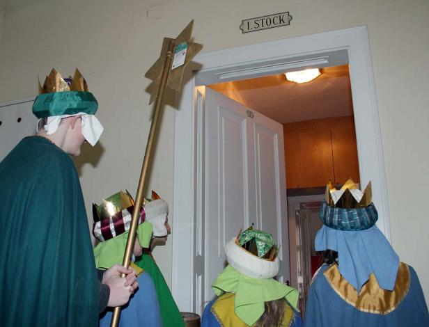 Sternsinger stehen vor einer Tür im ersten Stock.