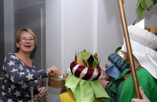 Sternsinger sammeln Spenden von einer Frau.