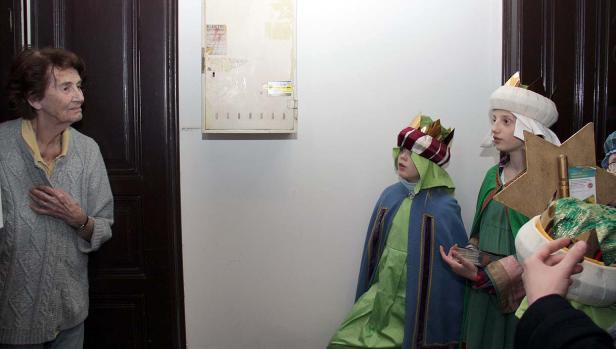 Eine ältere Frau beobachtet Kinder, die als die Heiligen Drei Könige verkleidet sind.