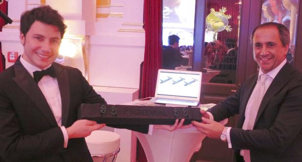 Zwei Männer im Anzug präsentieren einen „Greenrail“-Eisenbahnschwellen-Prototyp.