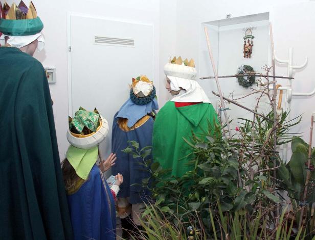 Eine Gruppe von als Heilige Drei Könige verkleideten Personen steht in einem Raum.