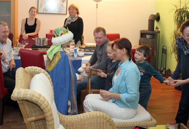 Eine Gruppe von Menschen sitzt an einem Tisch, während ein Kind verkleidet ist.