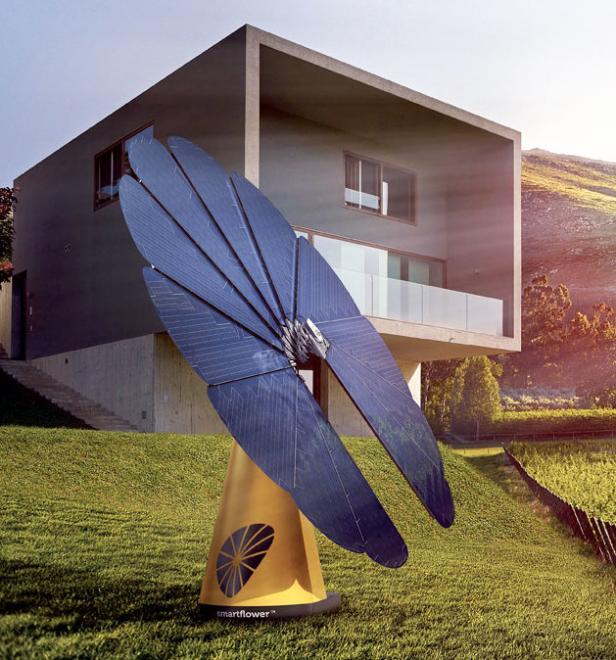 Eine Smartflower Solaranlage steht vor einem modernen Haus auf einer grünen Wiese.