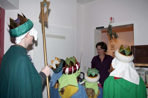 Eine Gruppe Sternsinger, verkleidet als die Heiligen Drei Könige, besucht ein Haus.