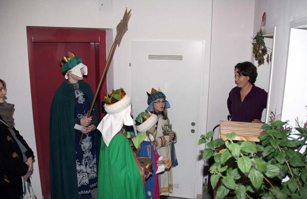 Sternsinger besuchen ein Haus und werden von einer Frau empfangen.