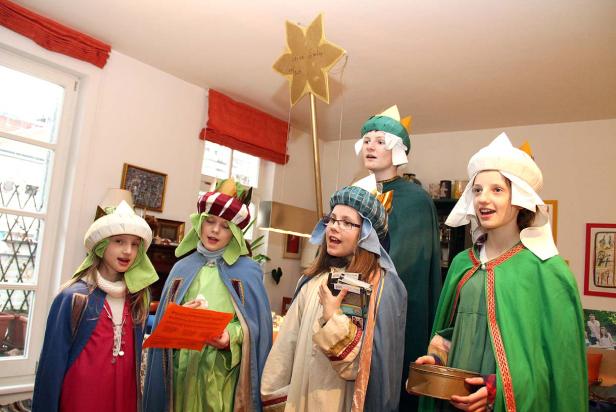 Eine Gruppe Kinder, verkleidet als die Heiligen Drei Könige, singt Weihnachtslieder.