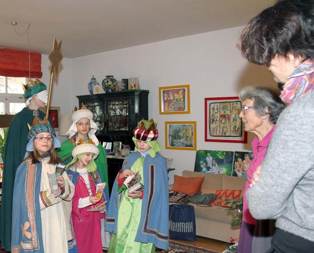 Kinder, verkleidet als die Heiligen Drei Könige, besuchen eine ältere Frau.