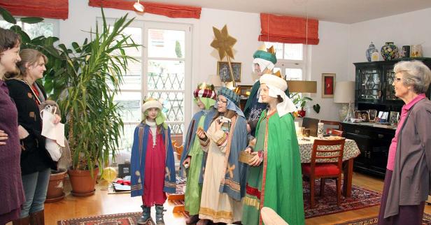 Eine Gruppe Kinder, verkleidet als die Heiligen Drei Könige, besuchen ein Haus.